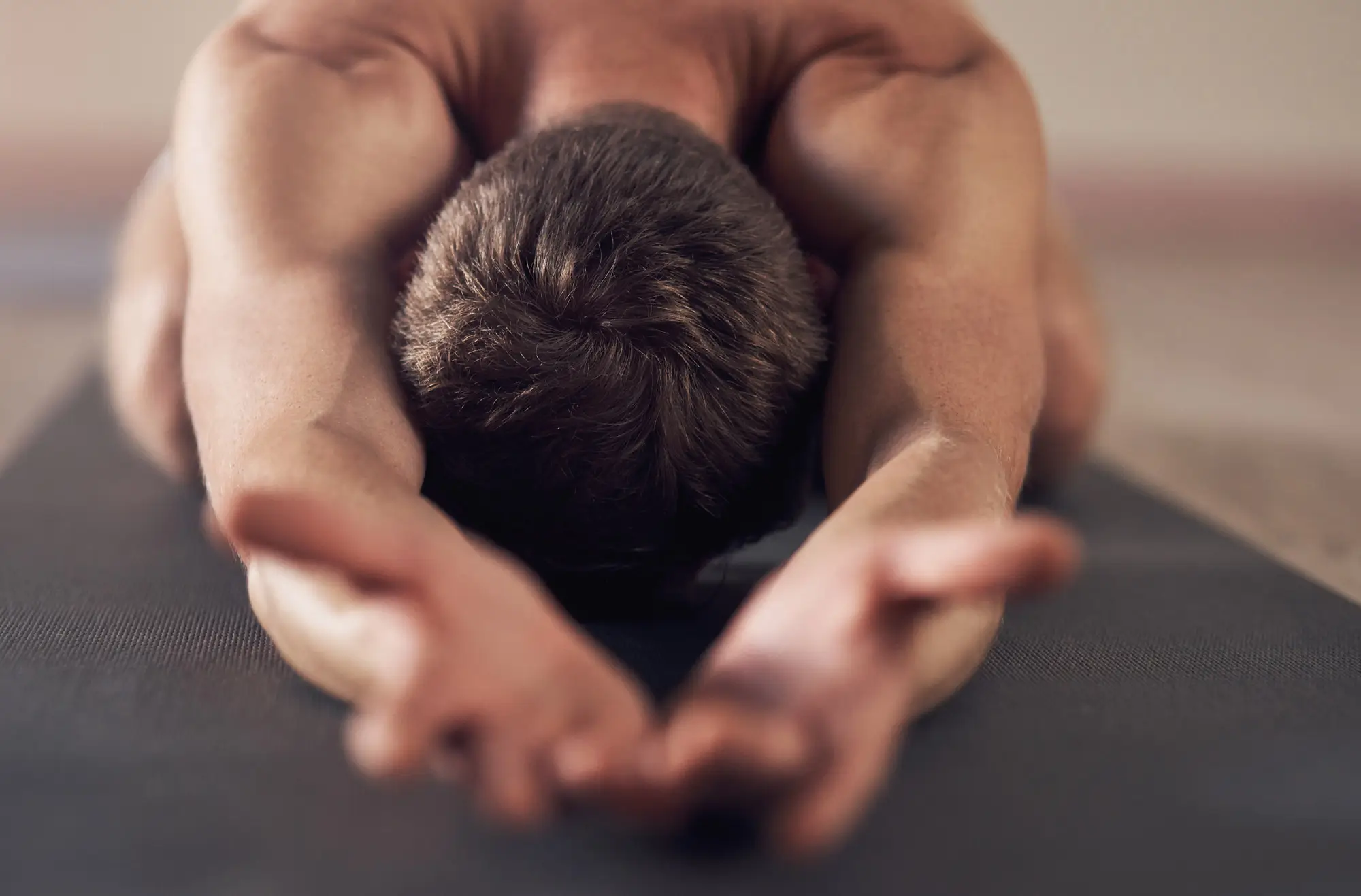 Mann auf Yoga Matte Nuad Thai Kopf nach unten Hände nach vorne ausgestreckt